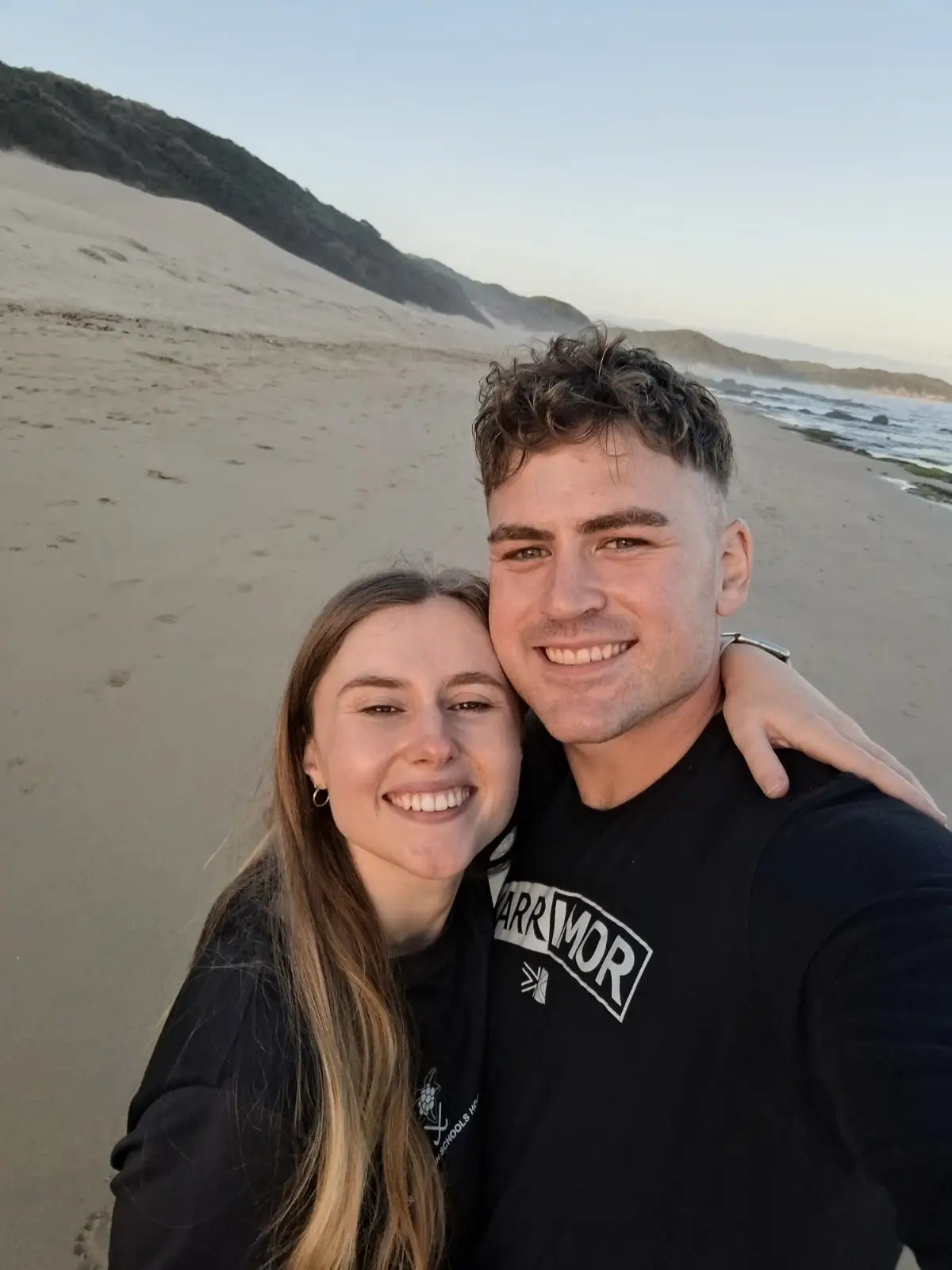 Ockert en Emja op die strand, met duine agter hulle.